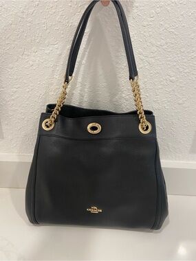 Coach Turnlock Edie shoulder bag in black with gold-tone chain handles.